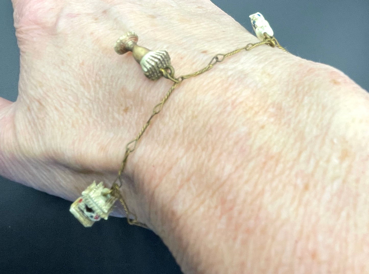 Delicate vintage / antique charm bracelet with slim gold tone chain and four early plastic or carved bone painted cracker charms