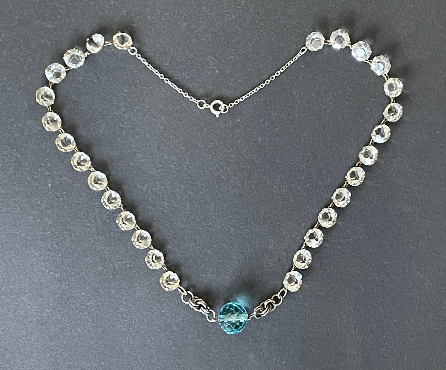 Vintage Art Deco clear paste riviere necklace with sapphire blue crystal bead and machine age link feature, bezel set open backed stones