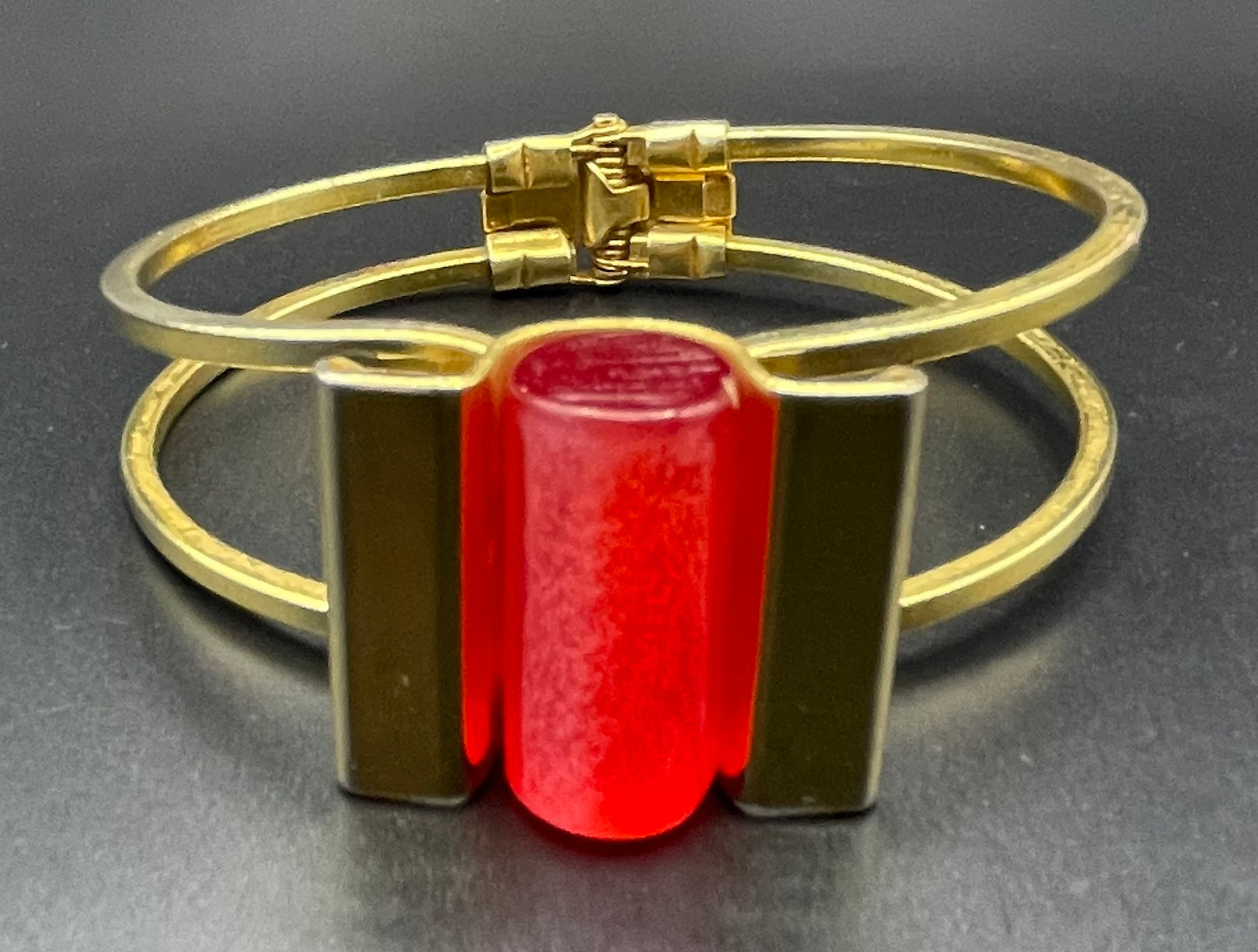 Vintage Jakob Bengel Art Deco machine age clamper bangle in shiny gold tone with a rich orange galalith cylinder