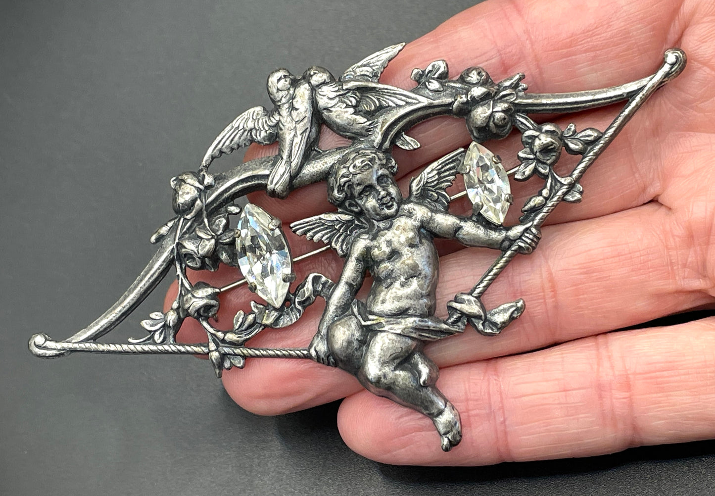 Large early Askew London, vintage cupid brooch in antique silver tone with marquise cut clear rhinestones, cherub / putti & love bird design