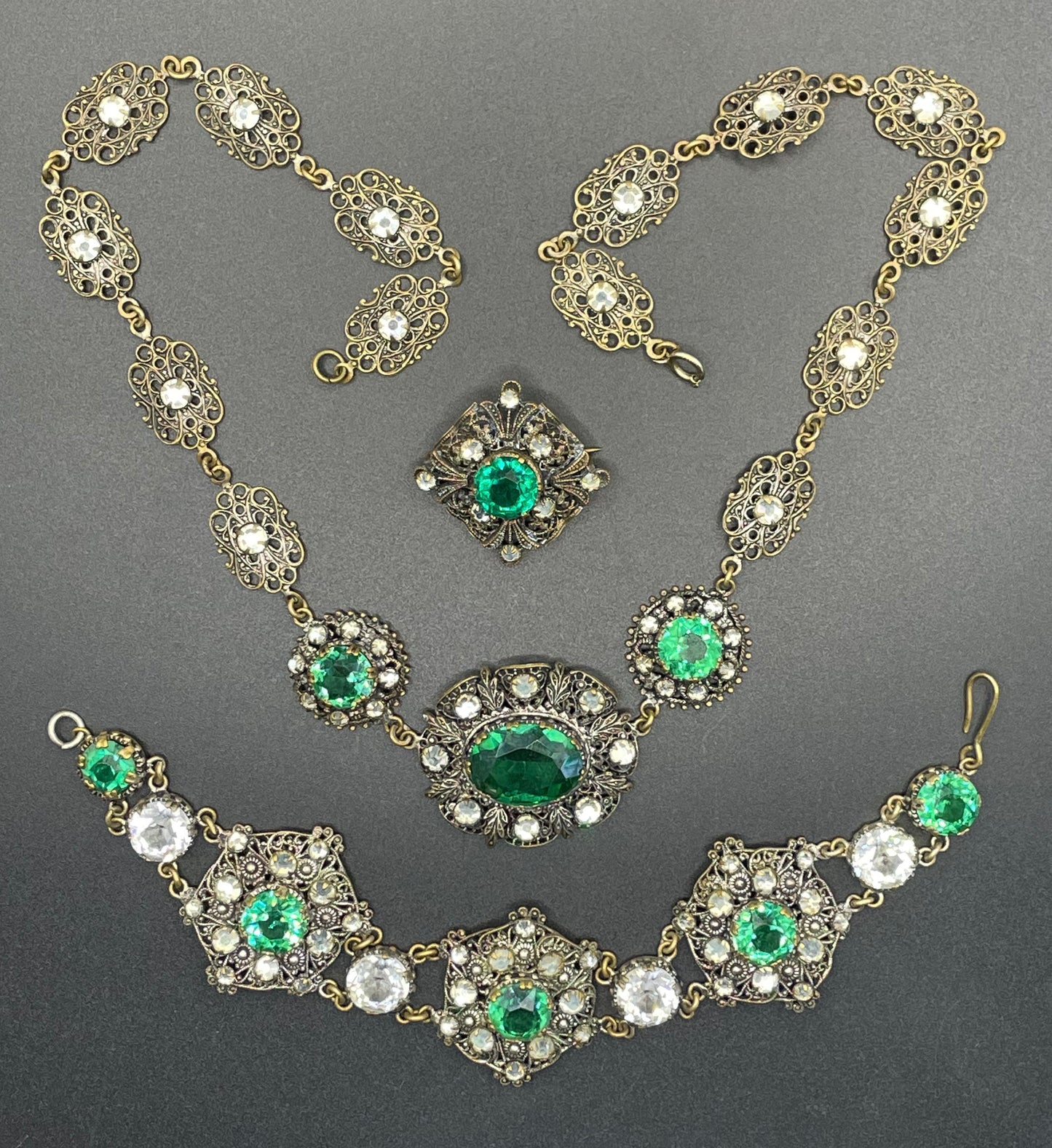 Vintage Art Deco Czech emerald green and clear glass rhinestone and gold tone filigree necklace, bracelet and brooch set, possibly Neiger
