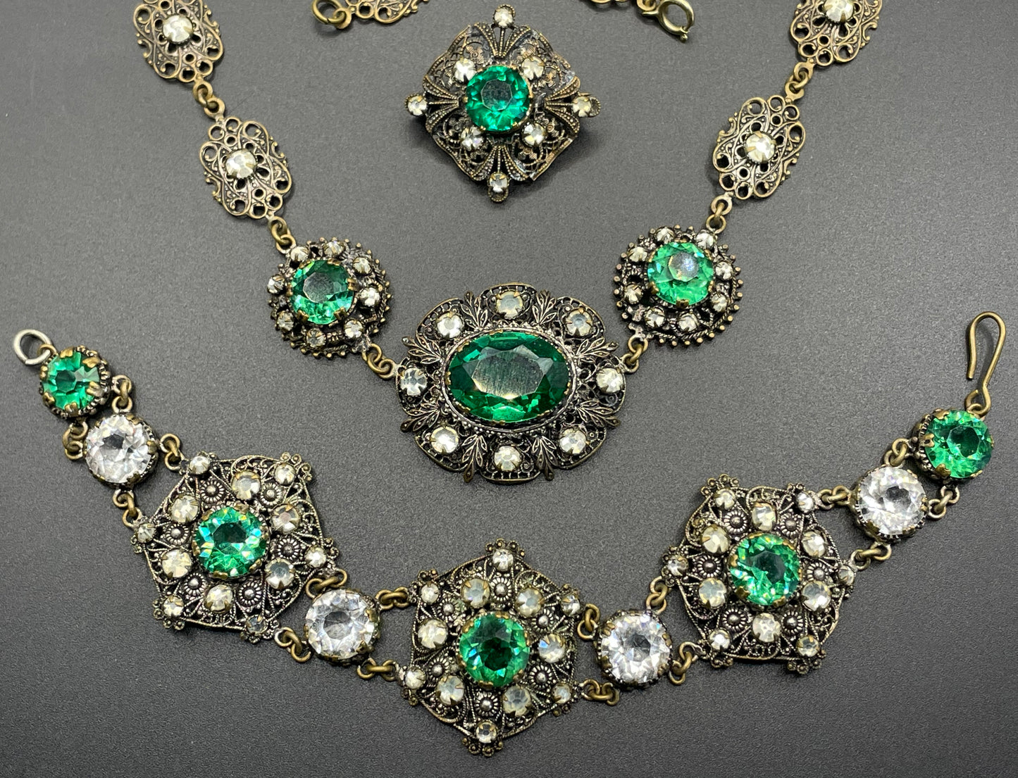 Vintage Art Deco Czech emerald green and clear glass rhinestone and gold tone filigree necklace, bracelet and brooch set, possibly Neiger