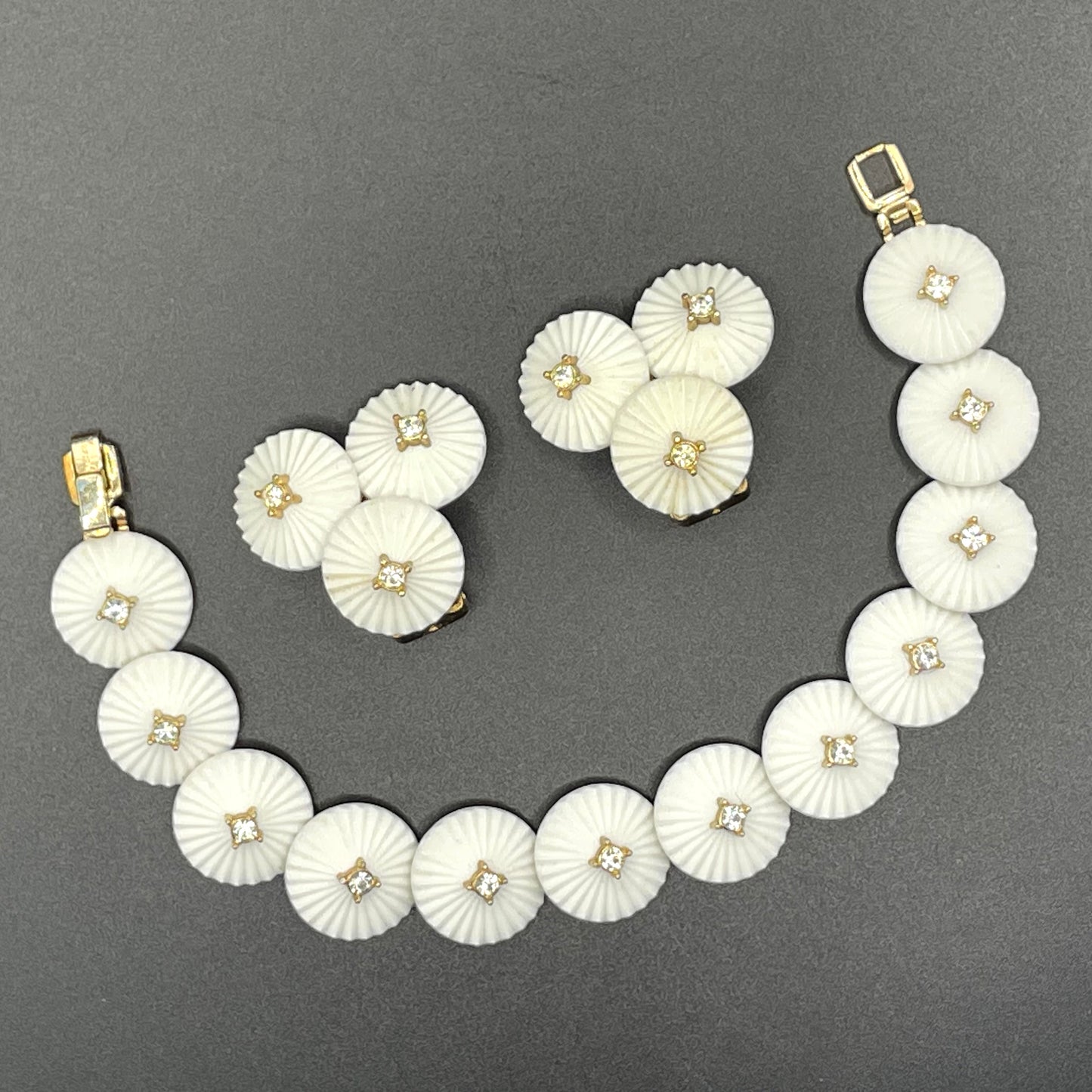 Vintage signed Trifari white celluloid plastic, clear rhinestone and gold tone panel bracelet and clip on earrings set, 1960s