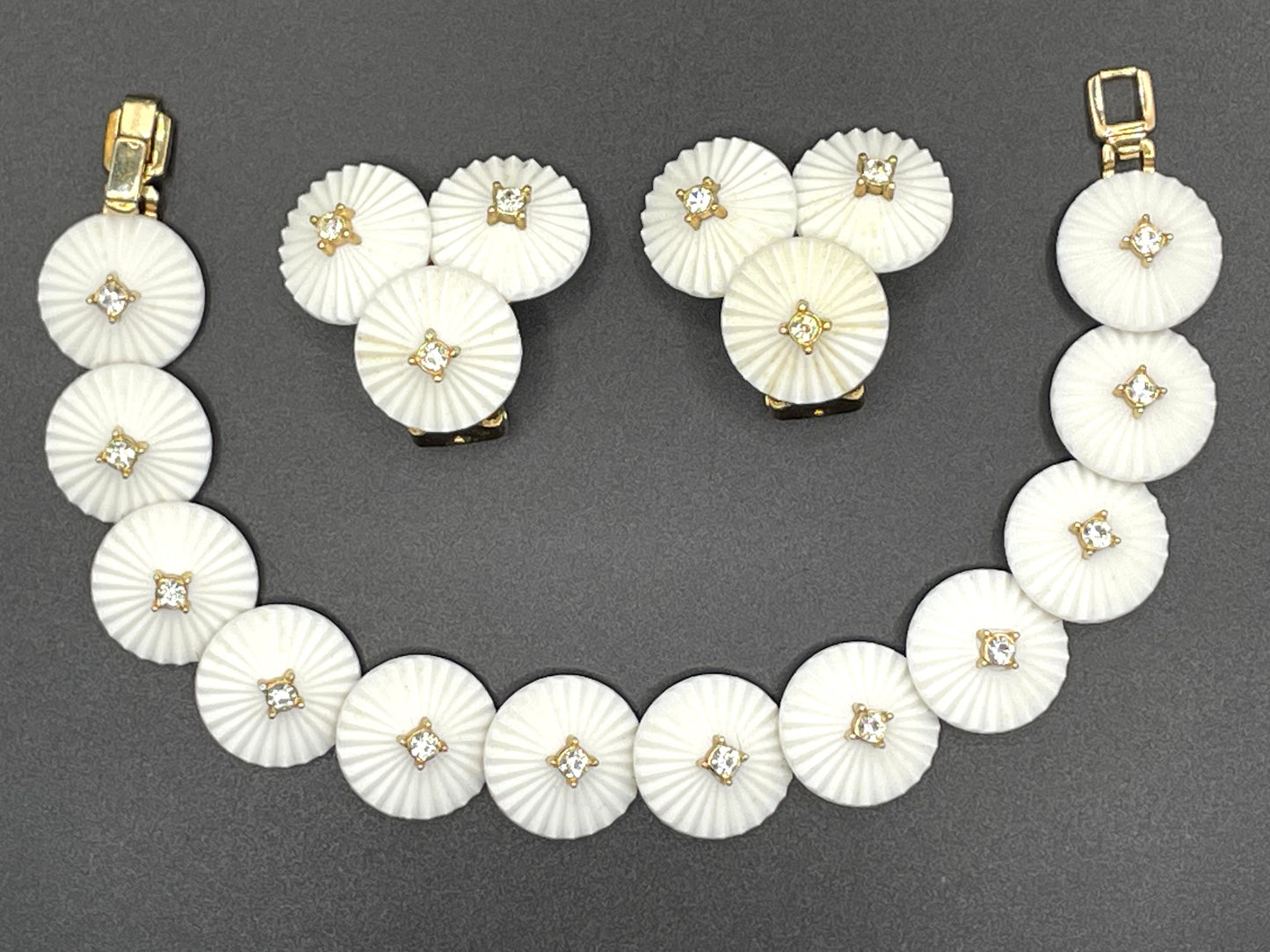 Vintage signed Trifari white celluloid plastic, clear rhinestone and gold tone panel bracelet and clip on earrings set, 1960s