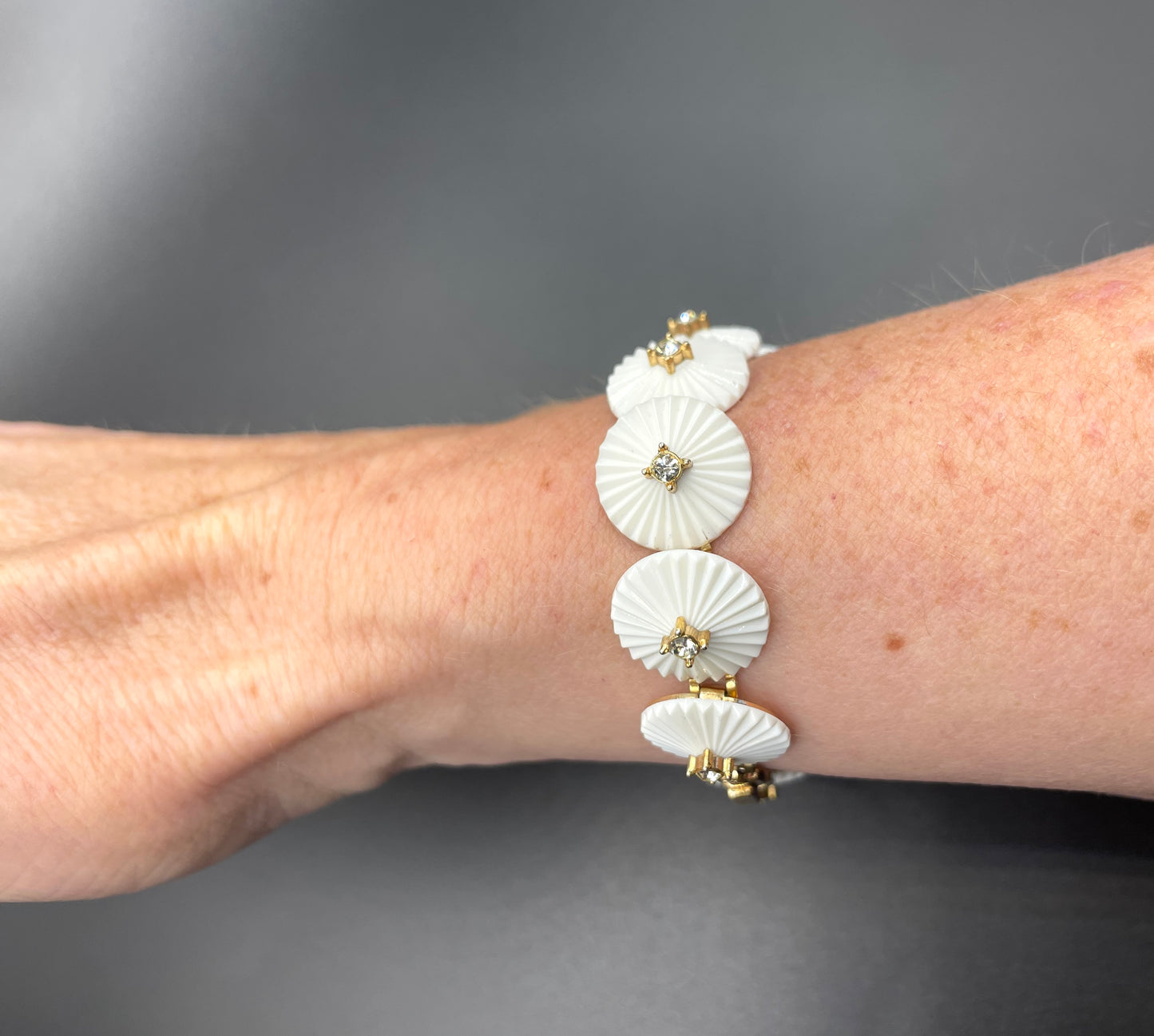 Vintage signed Trifari white celluloid plastic, clear rhinestone and gold tone panel bracelet and clip on earrings set, 1960s