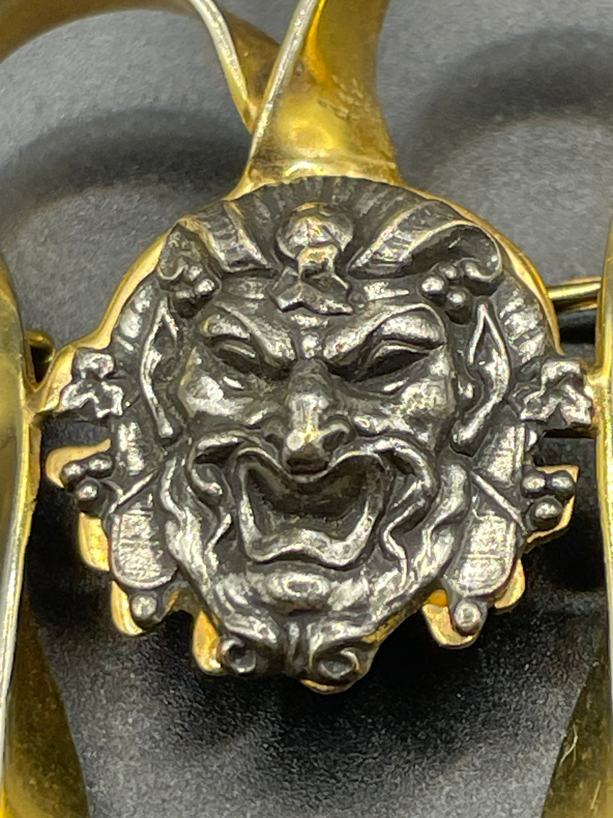 Unusual vintage 'Bacchus' face brooch with silver tone mounted on gold tone ribbon motif, French machine age construction, trombone clasp