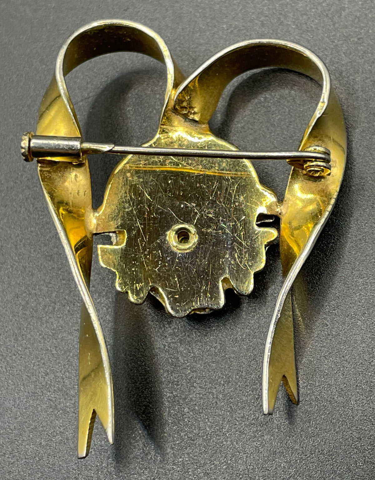 Unusual vintage 'Bacchus' face brooch with silver tone mounted on gold tone ribbon motif, French machine age construction, trombone clasp