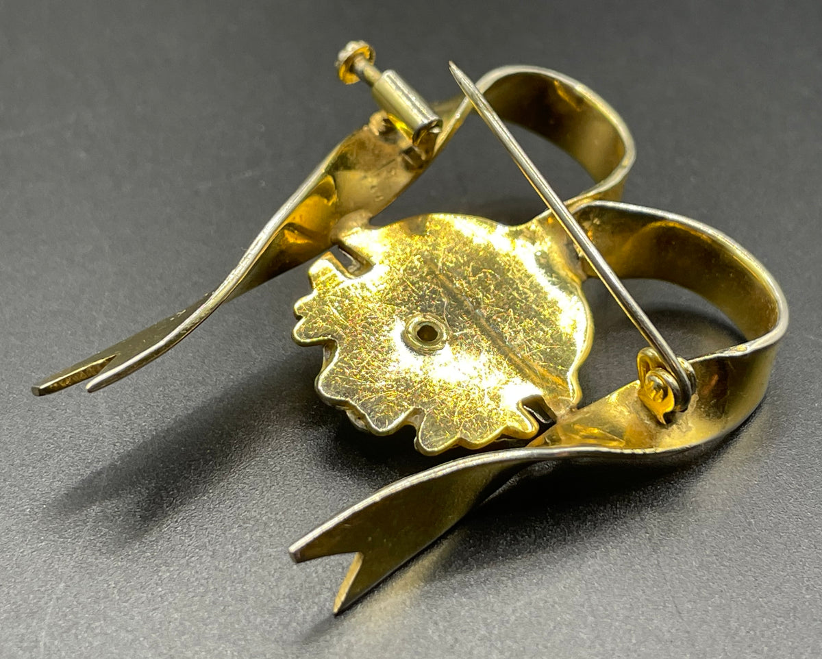 Unusual vintage 'Bacchus' face brooch with silver tone mounted on gold tone ribbon motif, French machine age construction, trombone clasp