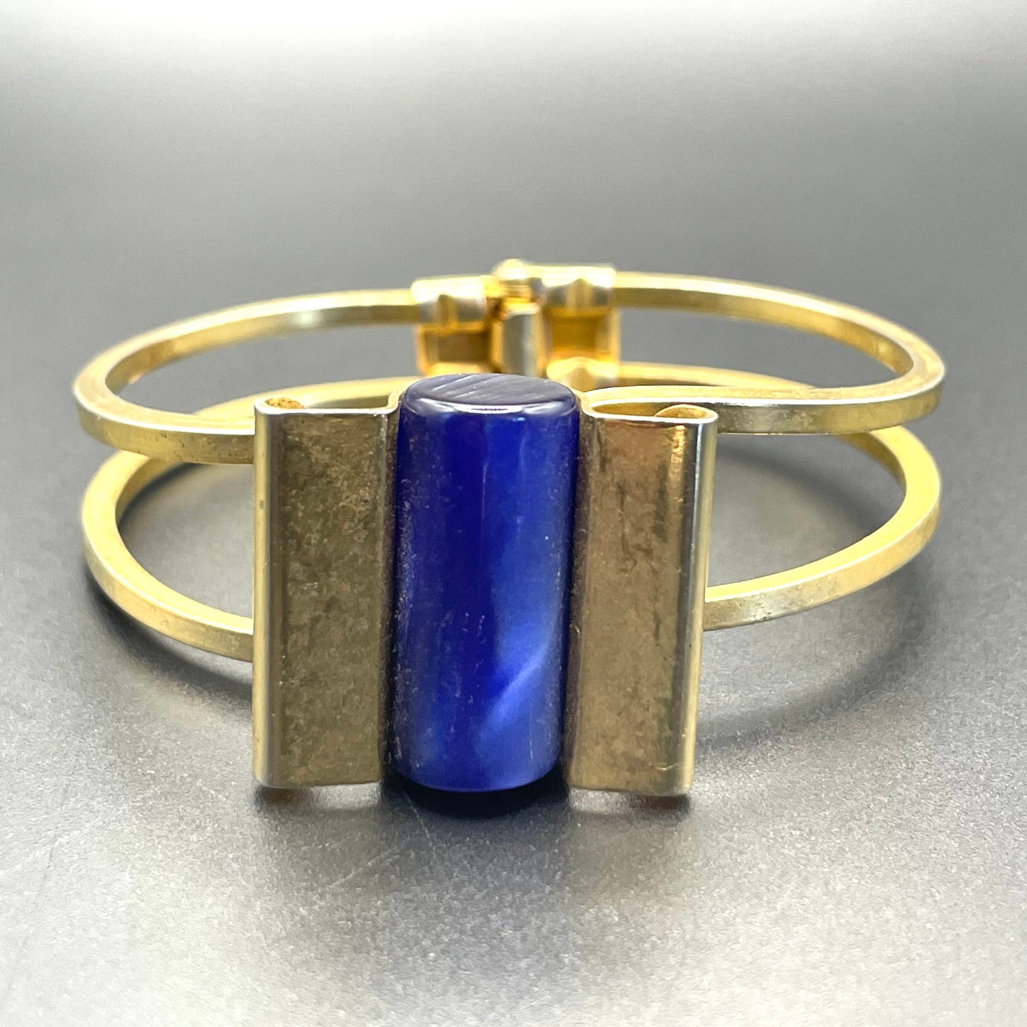 Vintage Jakob Bengel Art Deco machine age clamper bangle in shiny gold tone with a rich blue galalith cylinder