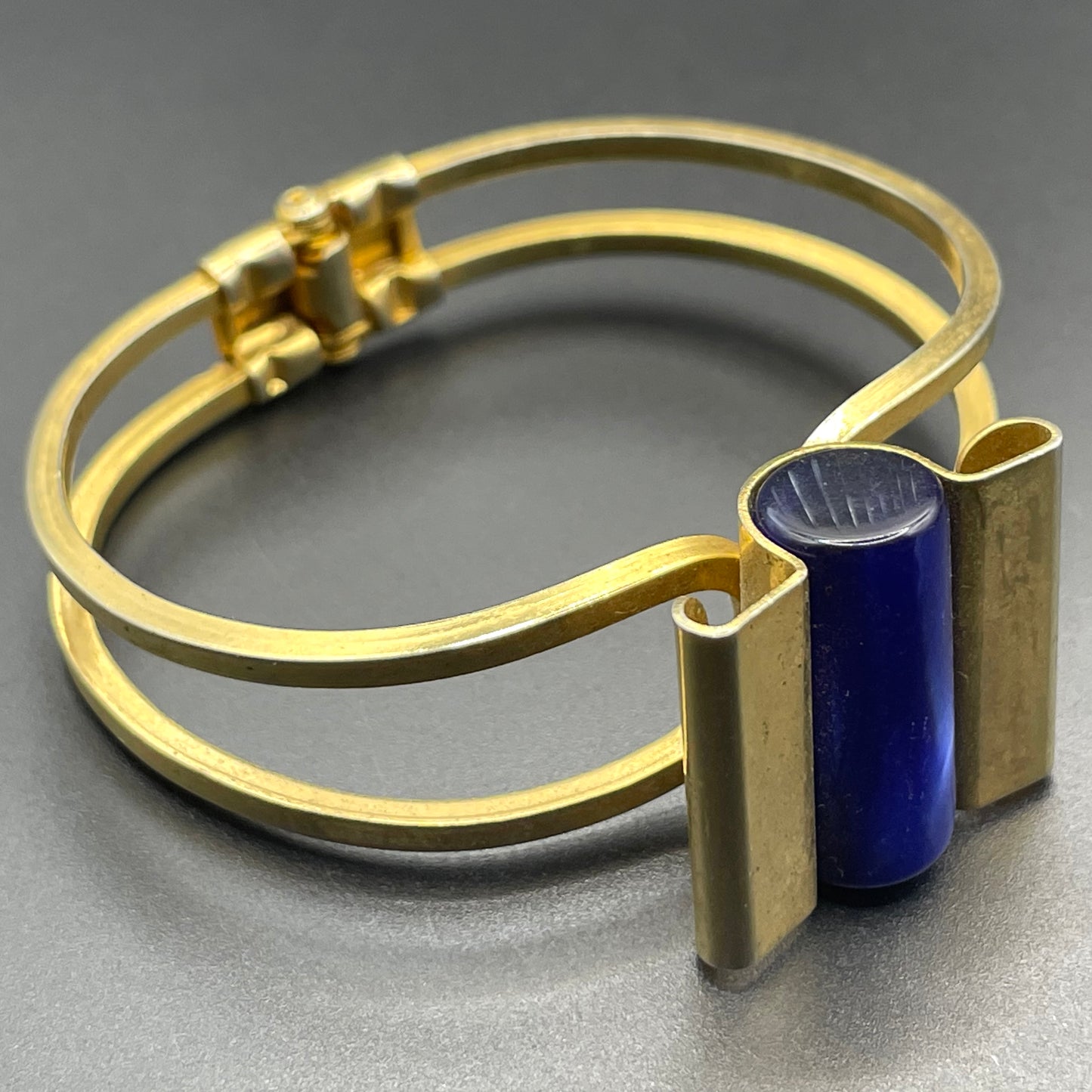Vintage Jakob Bengel Art Deco machine age clamper bangle in shiny gold tone with a rich blue galalith cylinder