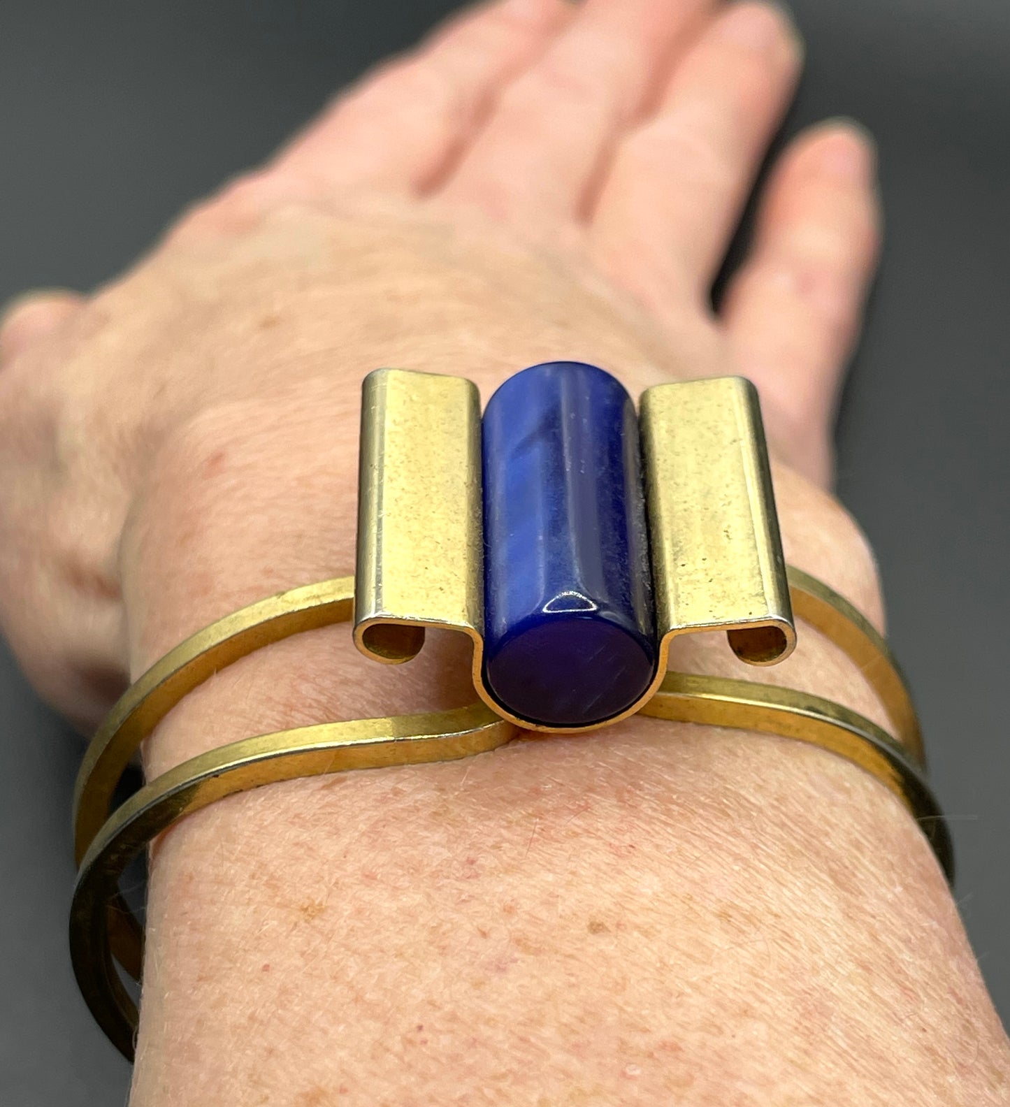 Vintage Jakob Bengel Art Deco machine age clamper bangle in shiny gold tone with a rich blue galalith cylinder