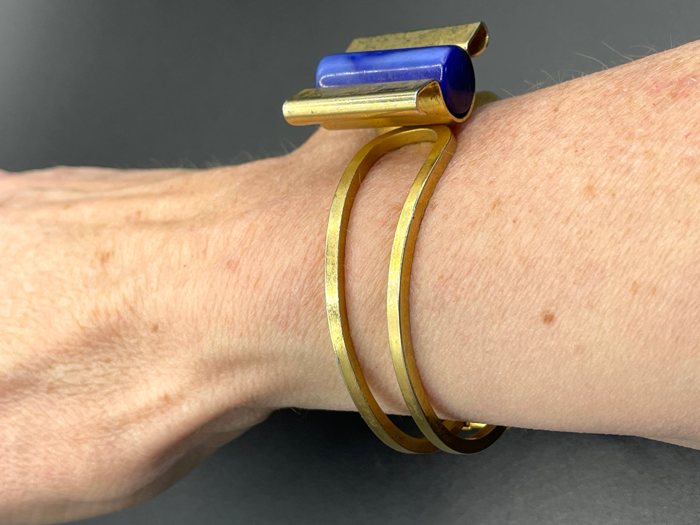 Vintage Jakob Bengel Art Deco machine age clamper bangle in shiny gold tone with a rich blue galalith cylinder
