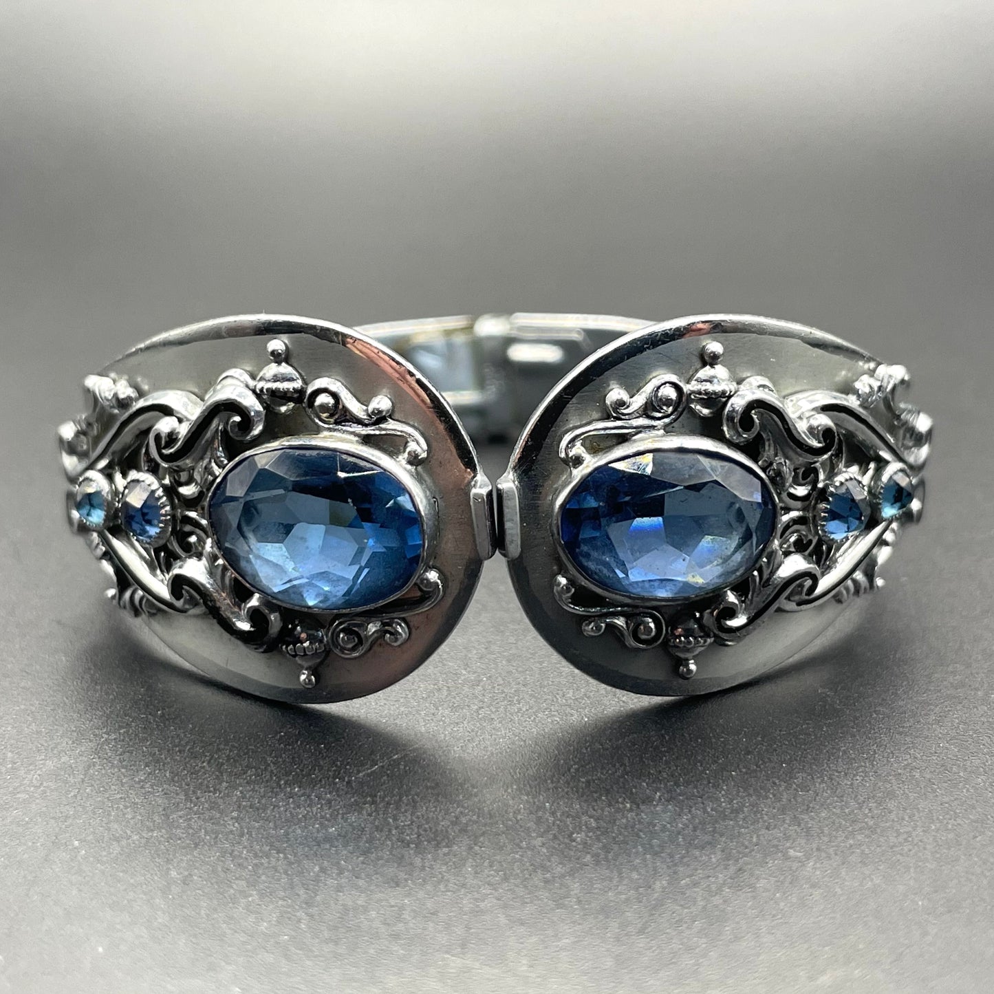 Vintage Neiger brothers sapphire blue rhinestone ornate Art Deco hinged clamper bangle set in silver tone with black enamel accents