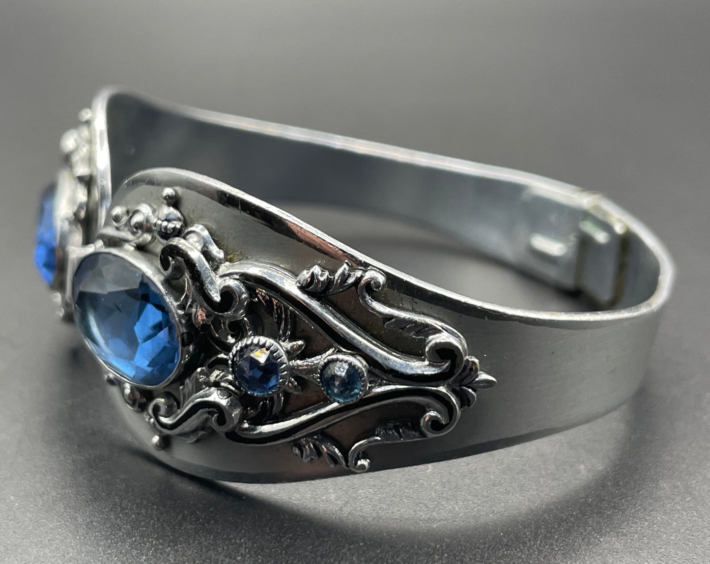 Vintage Neiger brothers sapphire blue rhinestone ornate Art Deco hinged clamper bangle set in silver tone with black enamel accents