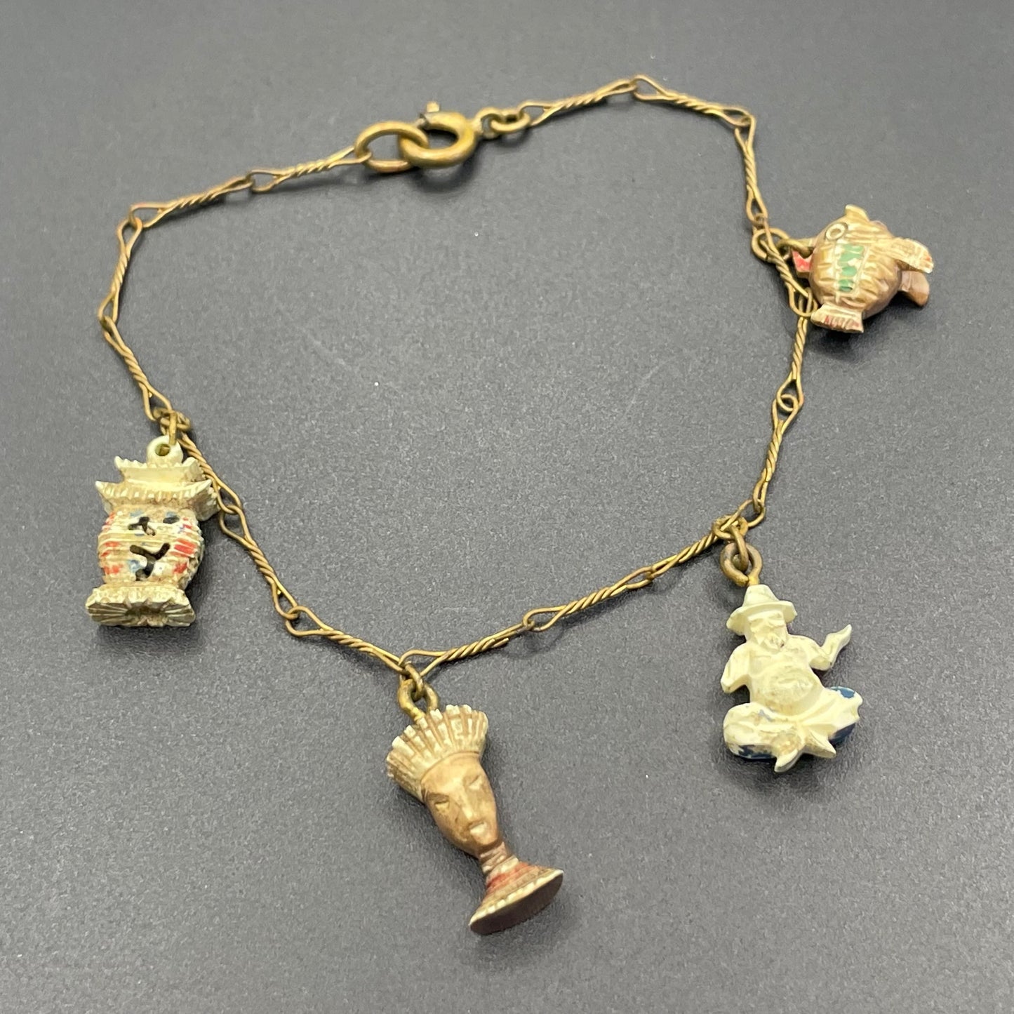 Delicate vintage / antique charm bracelet with slim gold tone chain and four early plastic or carved bone painted cracker charms