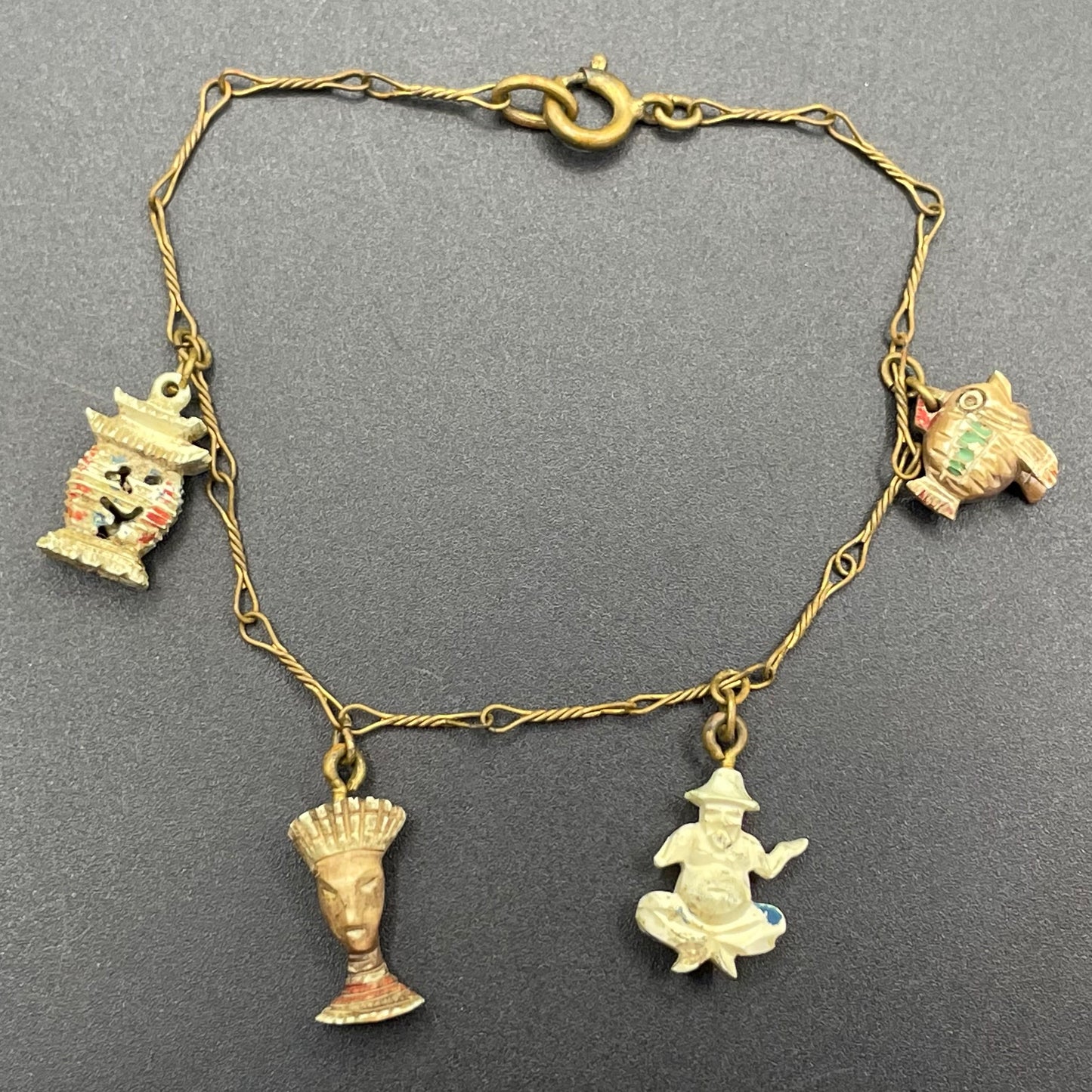 Delicate vintage / antique charm bracelet with slim gold tone chain and four early plastic or carved bone painted cracker charms
