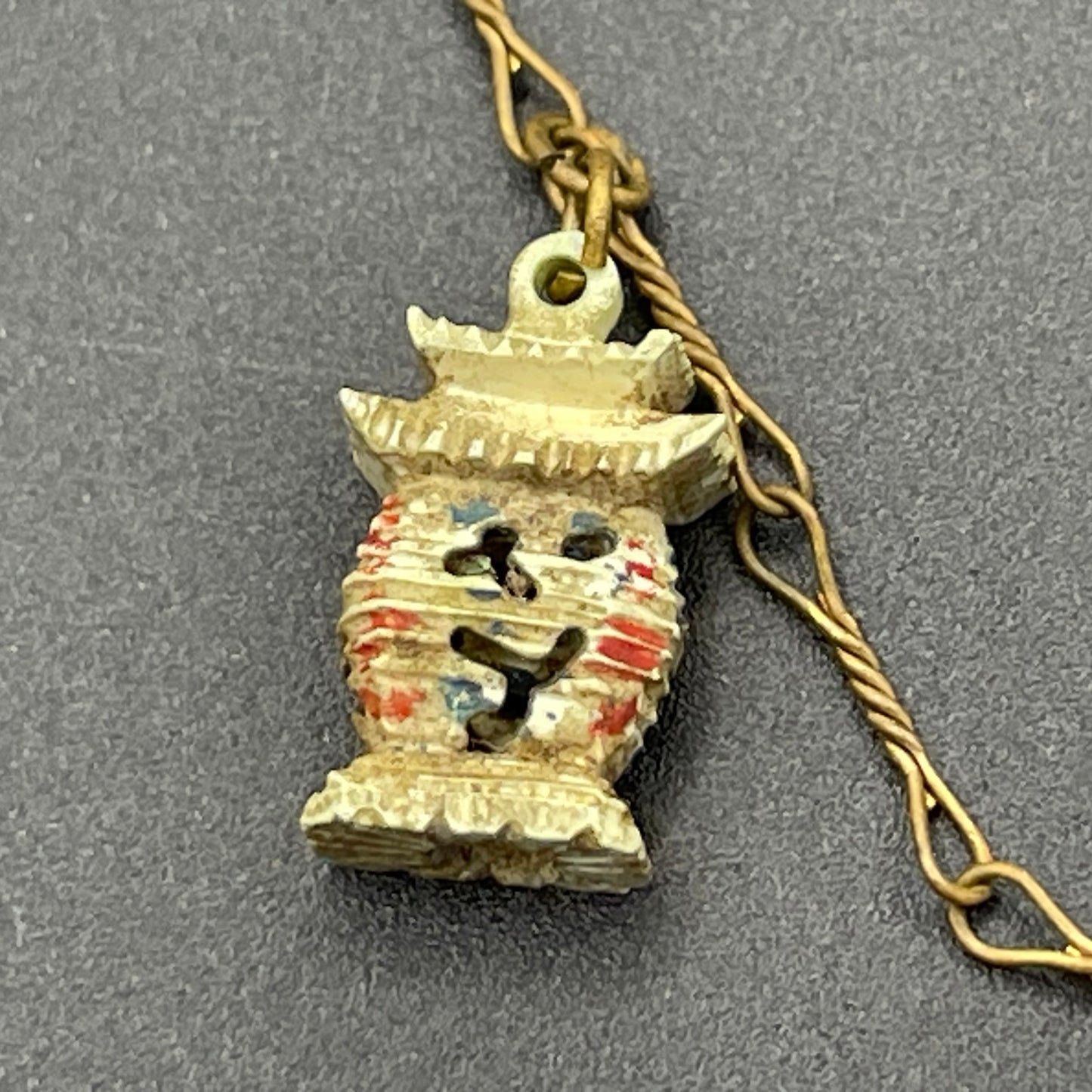 Delicate vintage / antique charm bracelet with slim gold tone chain and four early plastic or carved bone painted cracker charms