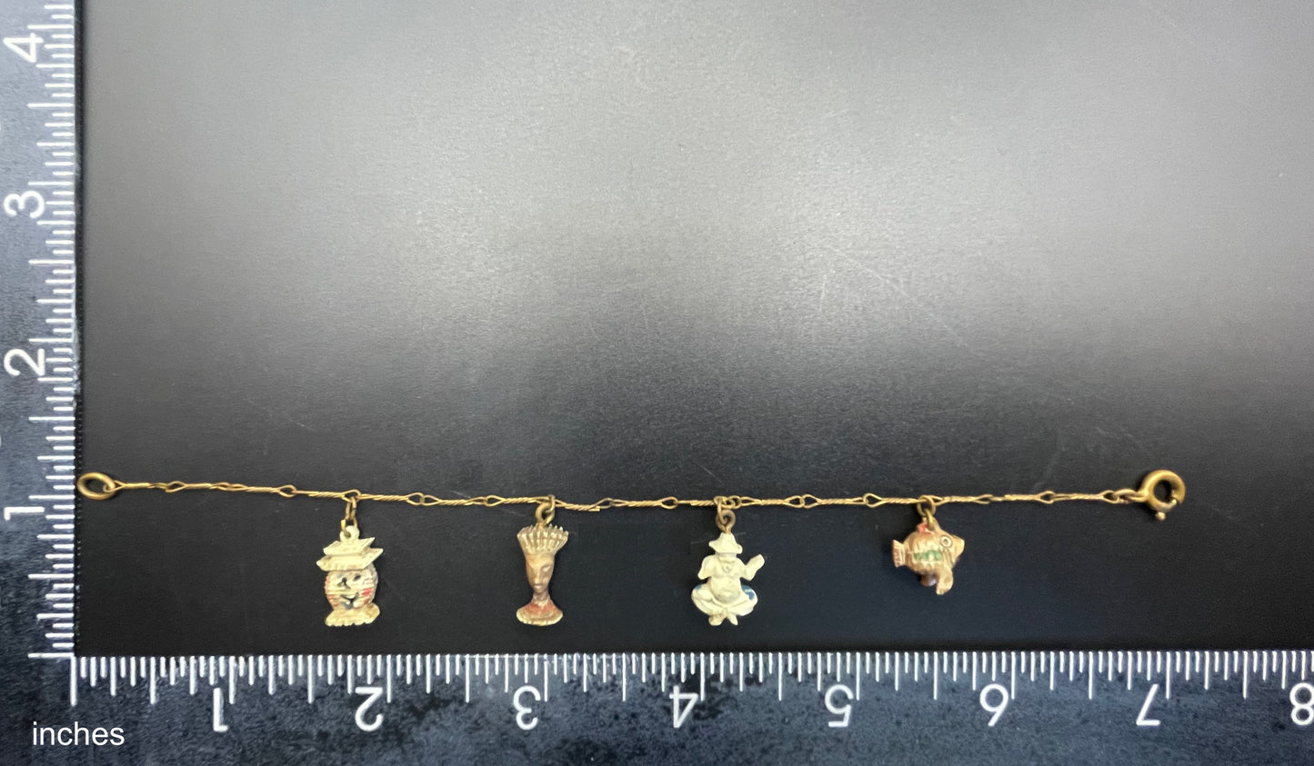 Delicate vintage / antique charm bracelet with slim gold tone chain and four early plastic or carved bone painted cracker charms
