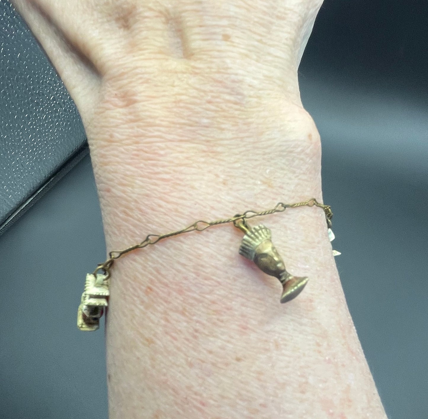 Delicate vintage / antique charm bracelet with slim gold tone chain and four early plastic or carved bone painted cracker charms