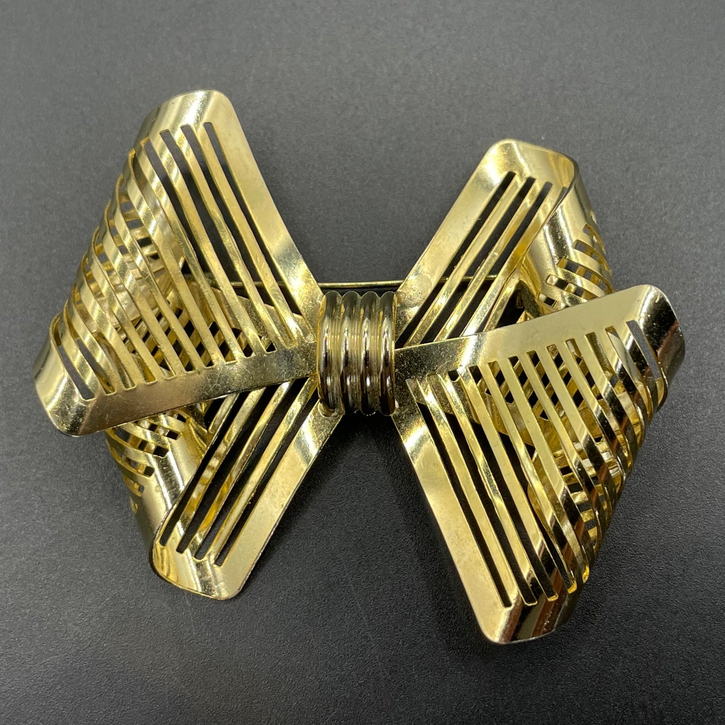 Vintage Art Deco machine age shiny gold tone stylised pierced metal geometric bow ribbon brooch, 1930s