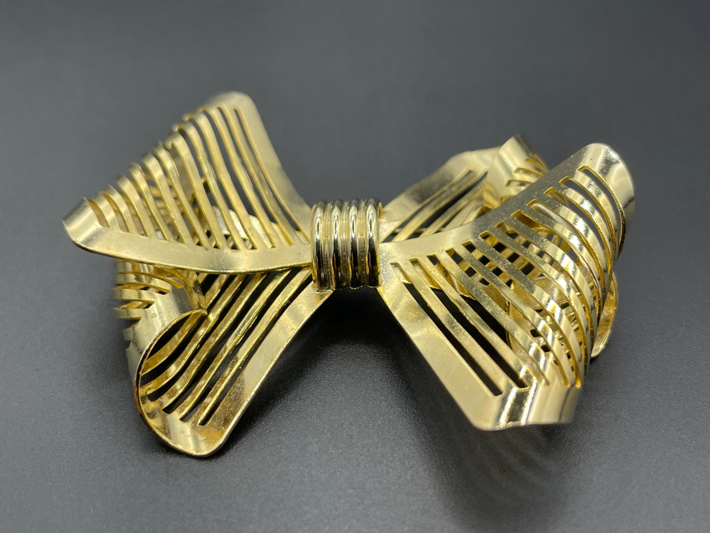 Vintage Art Deco machine age shiny gold tone stylised pierced metal geometric bow ribbon brooch, 1930s