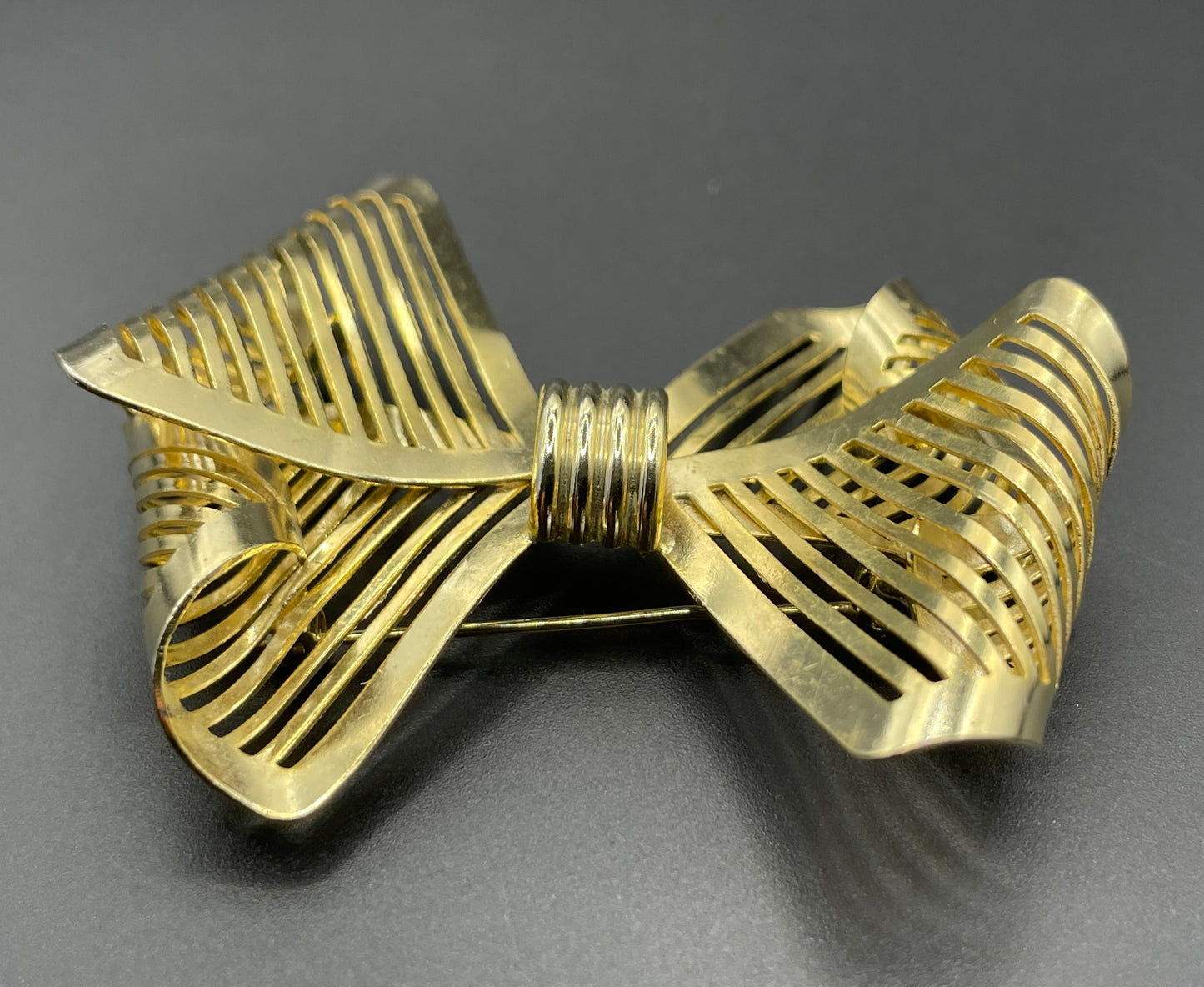 Vintage Art Deco machine age shiny gold tone stylised pierced metal geometric bow ribbon brooch, 1930s