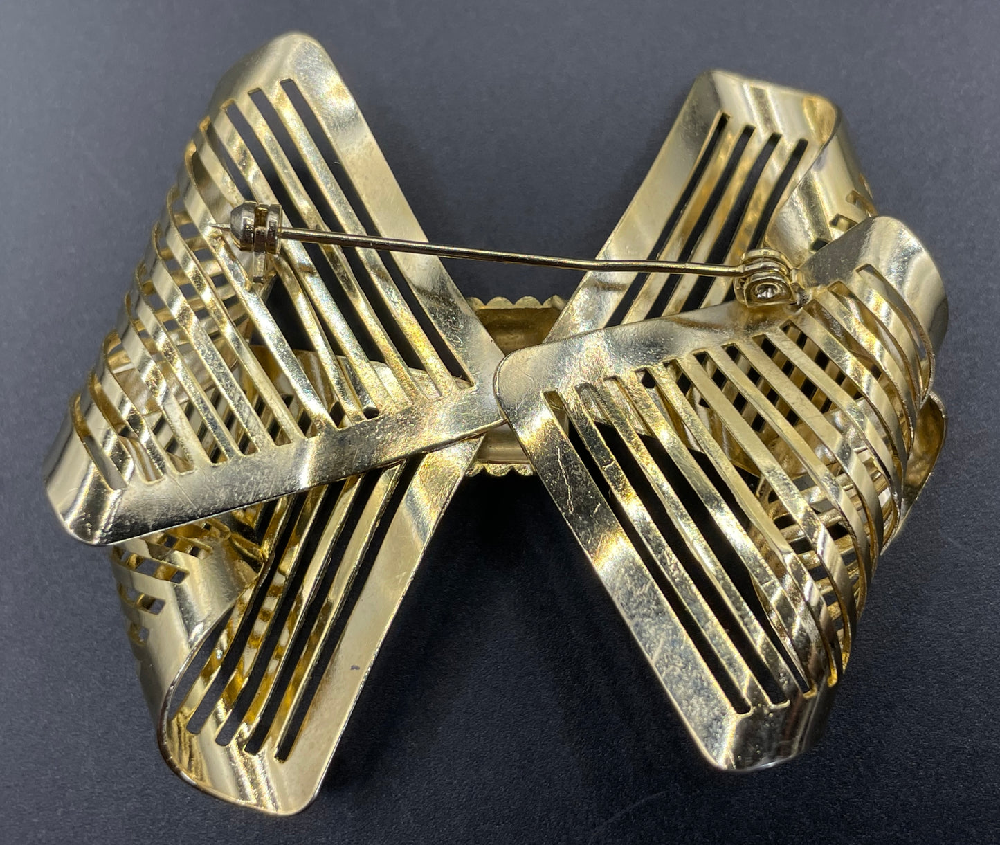Vintage Art Deco machine age shiny gold tone stylised pierced metal geometric bow ribbon brooch, 1930s