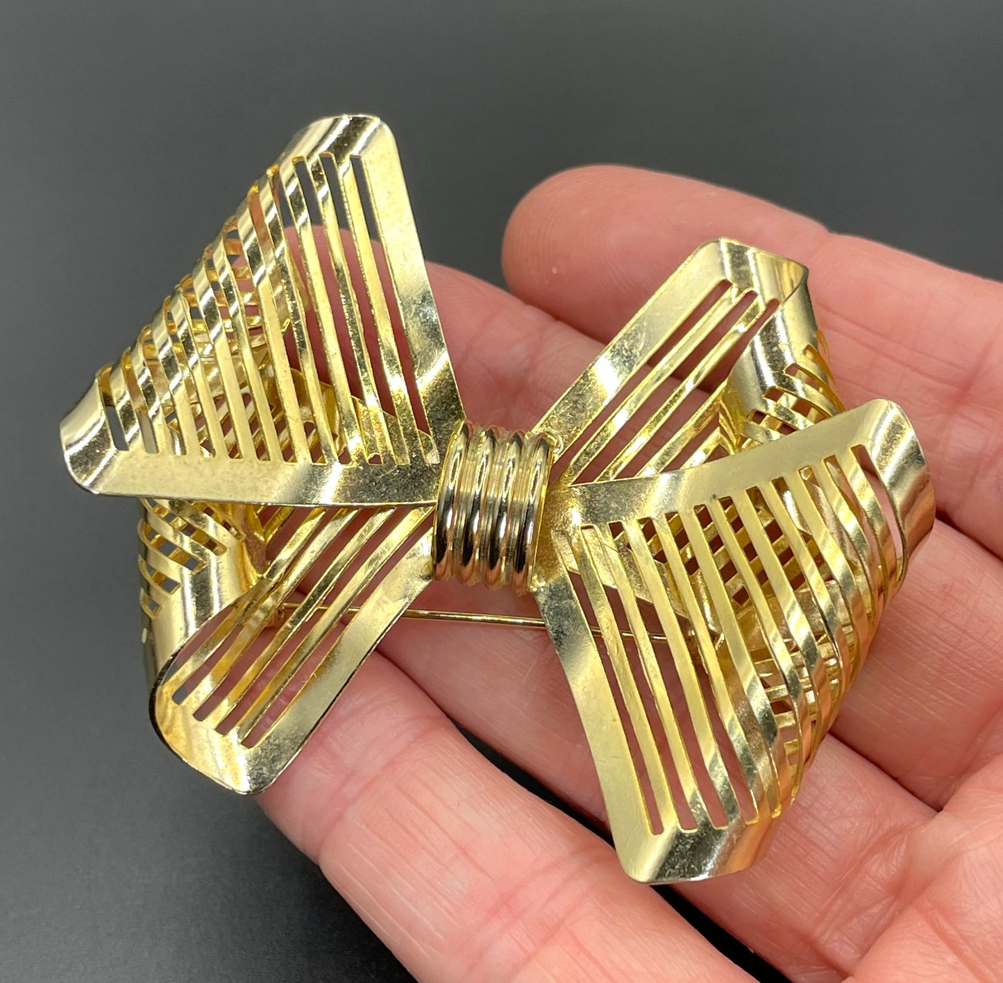 Vintage Art Deco machine age shiny gold tone stylised pierced metal geometric bow ribbon brooch, 1930s