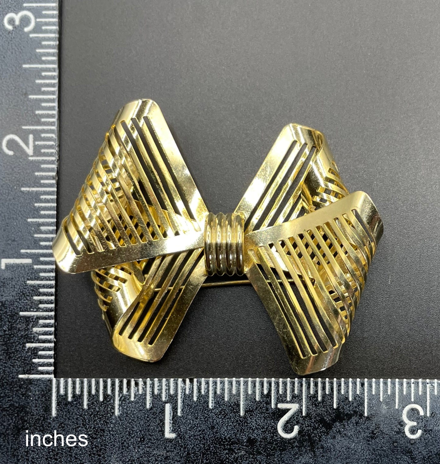Vintage Art Deco machine age shiny gold tone stylised pierced metal geometric bow ribbon brooch, 1930s