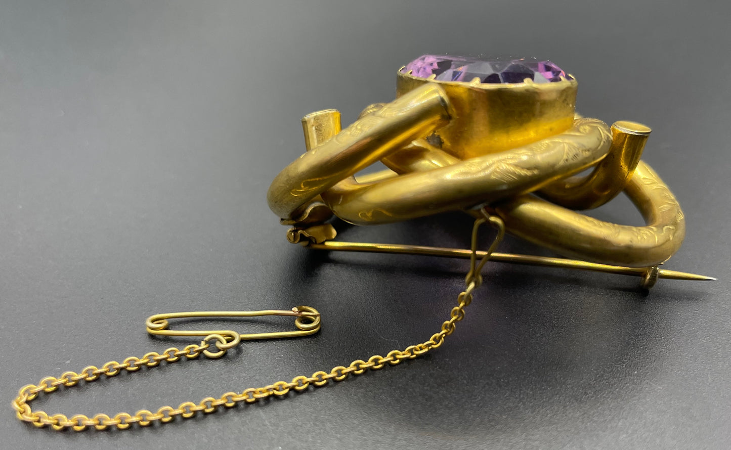 Antique Victorian Scottish chased pinchbeck or gold filled / rolled gold large love knot brooch with large purple paste rhinestone