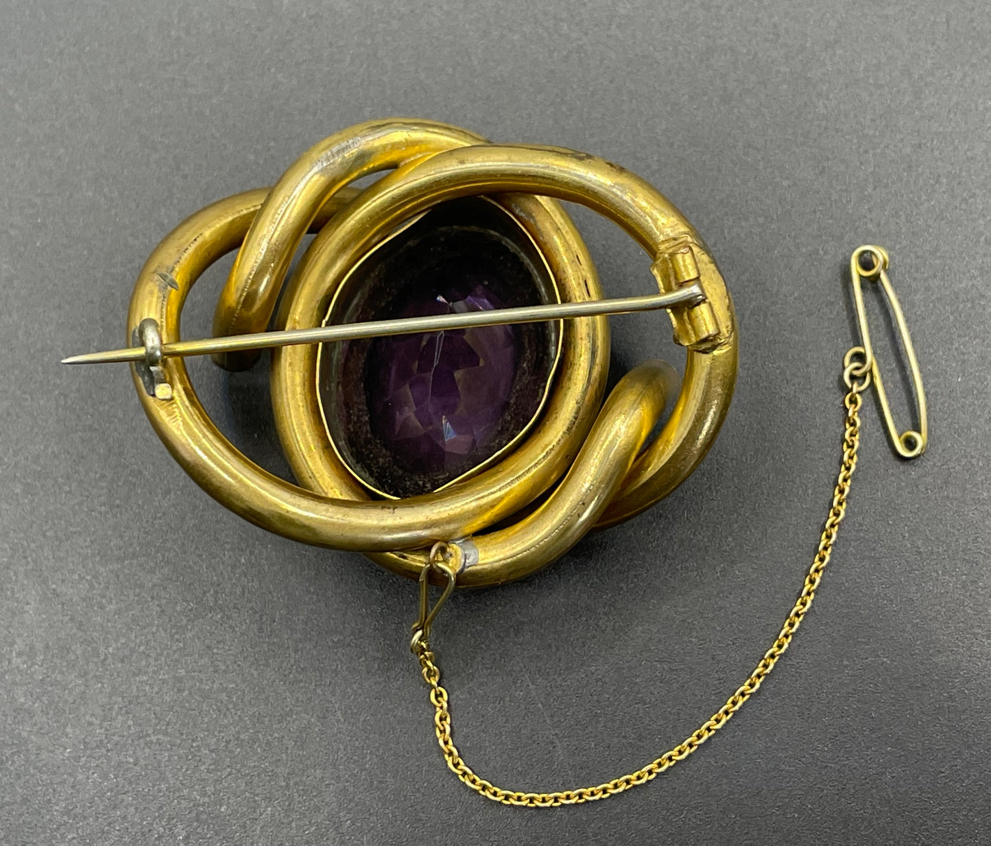 Antique Victorian Scottish chased pinchbeck or gold filled / rolled gold large love knot brooch with large purple paste rhinestone