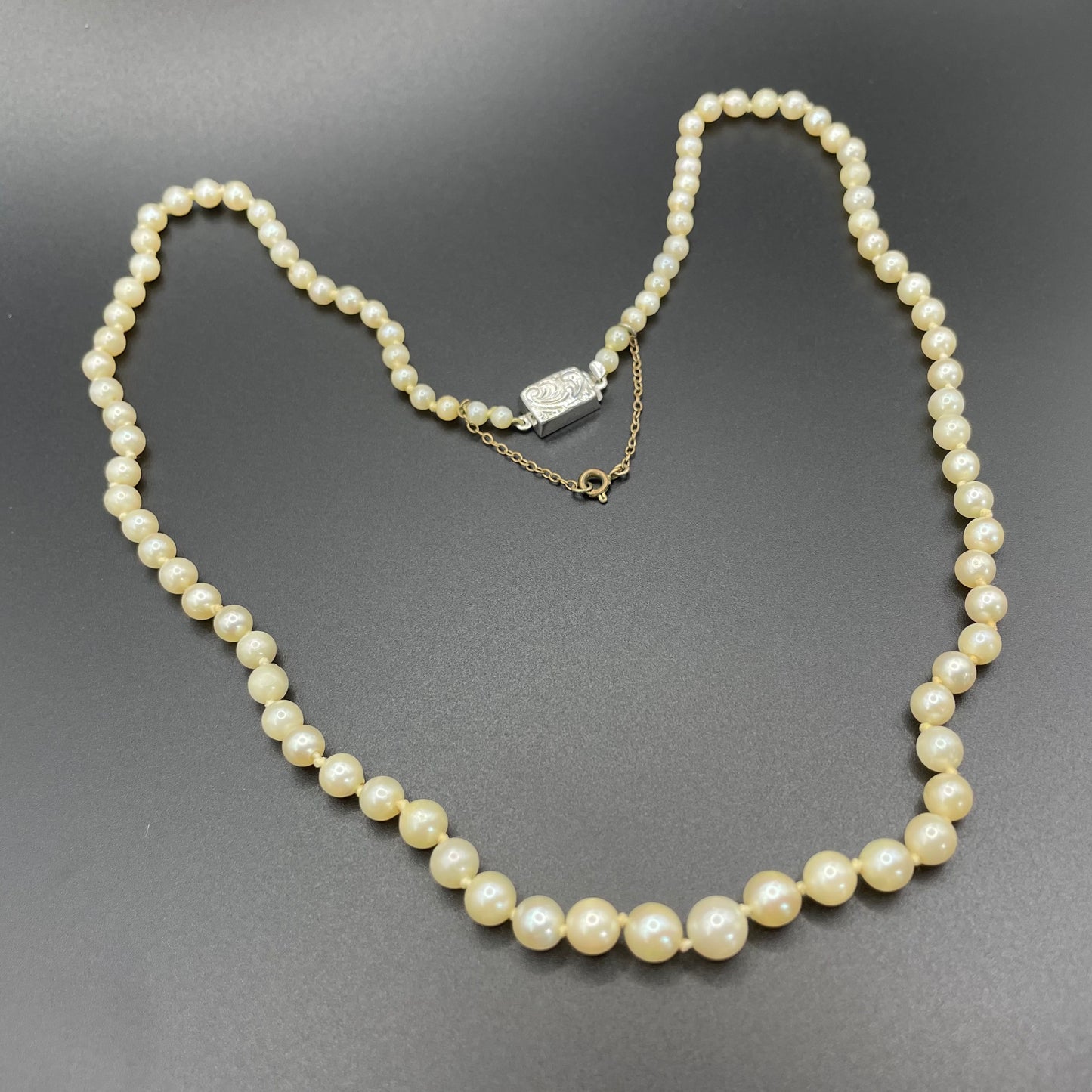 Vintage real cultured pearl necklace, graduated in size, hand-knotted, pretty engraved sterling silver clasp, mid-length