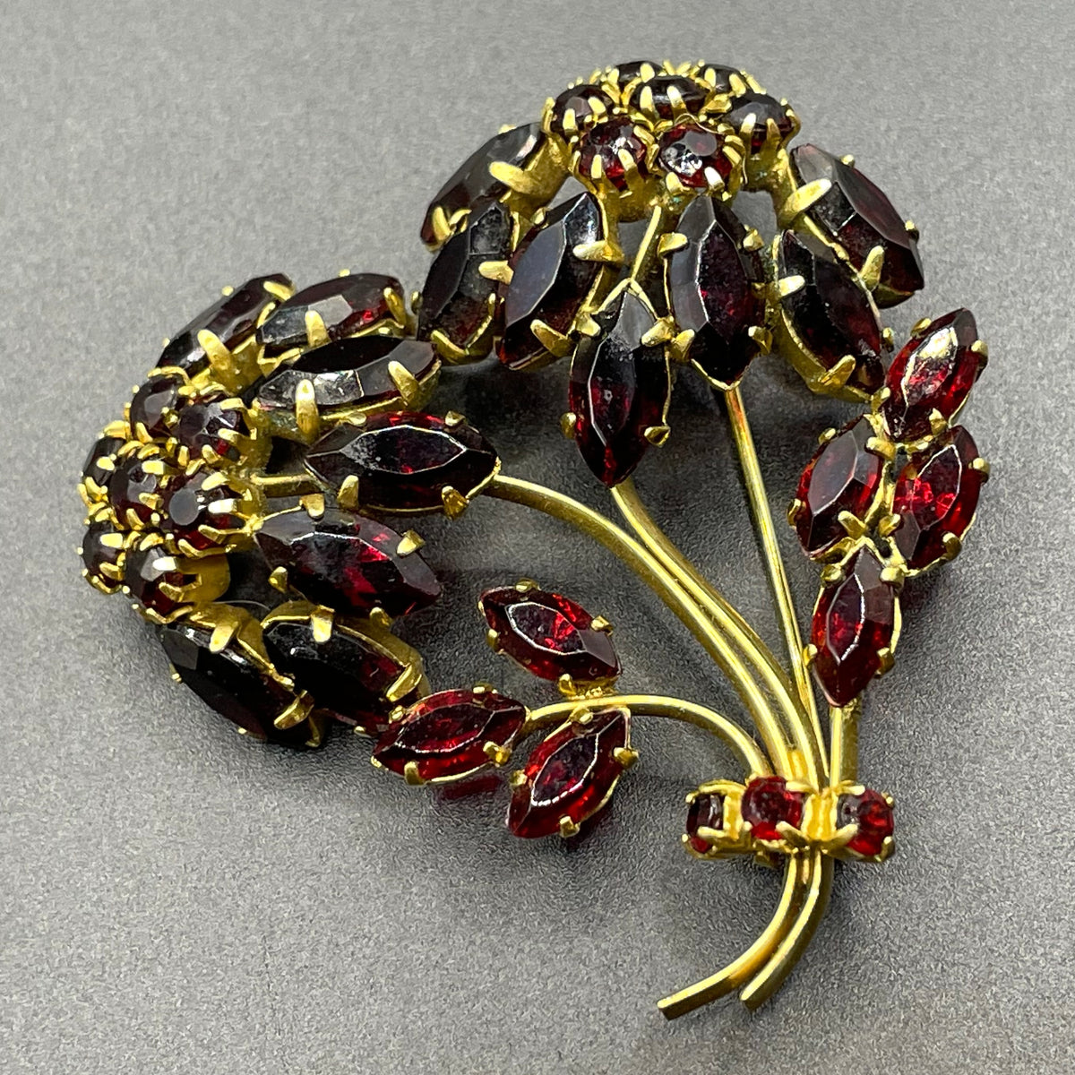 Vintage red garnet glass flower bouquet brooch, with rhinestones set open-backed in gold tone