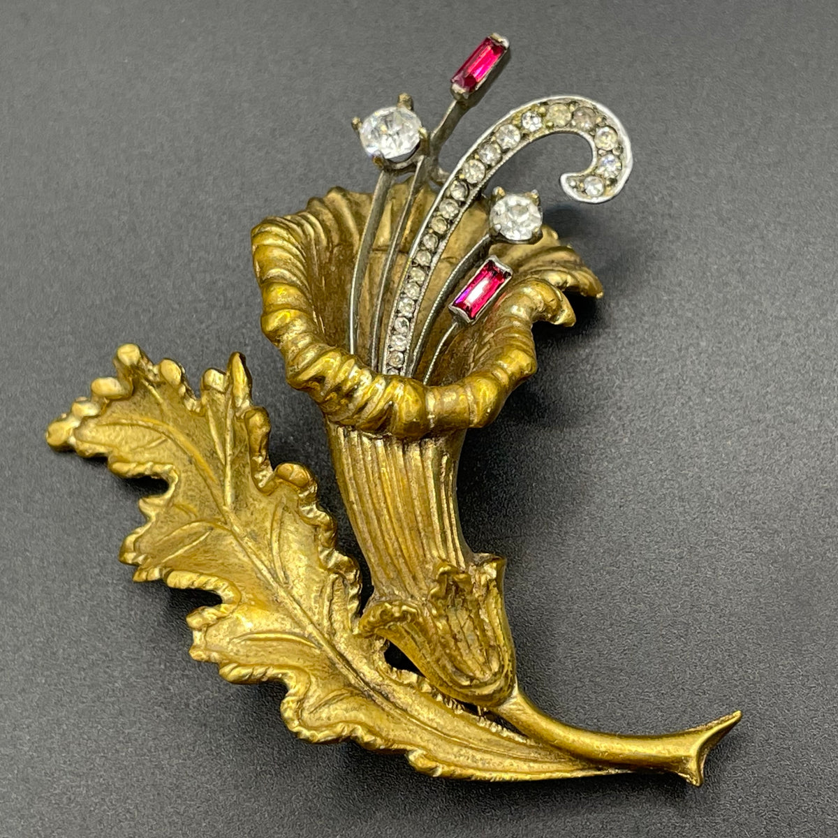 Vintage lily flower and leaf design DeRosa style brooch in gold and silver tone with clear and red rhinestones