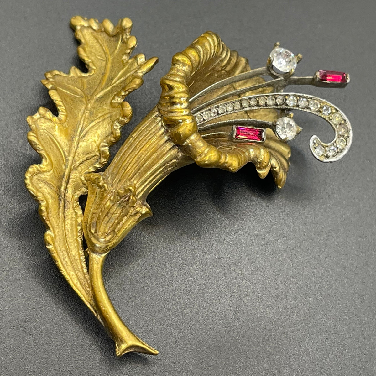 Vintage lily flower and leaf design DeRosa style brooch in gold and silver tone with clear and red rhinestones