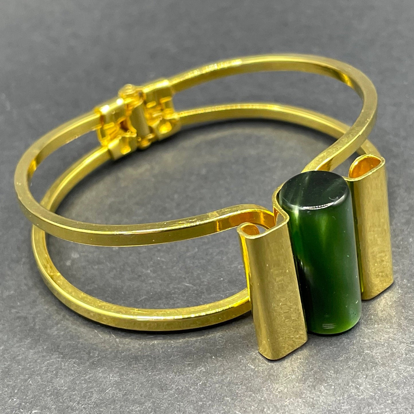 Vintage Jakob Bengel Art Deco machine age clamper bangle in shiny gold tone with a rich green galalith cylinder