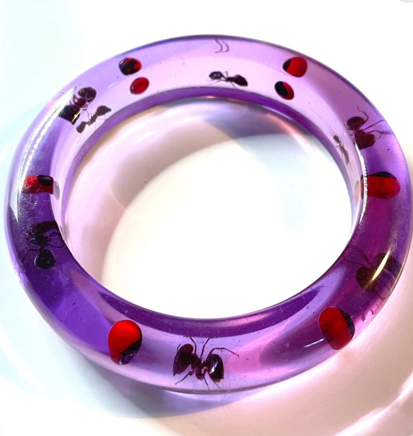 Vintage inclusion bangle with ants and red accents in transparent purple lucite style plastic resin, gives a glow under ultraviolet UV light