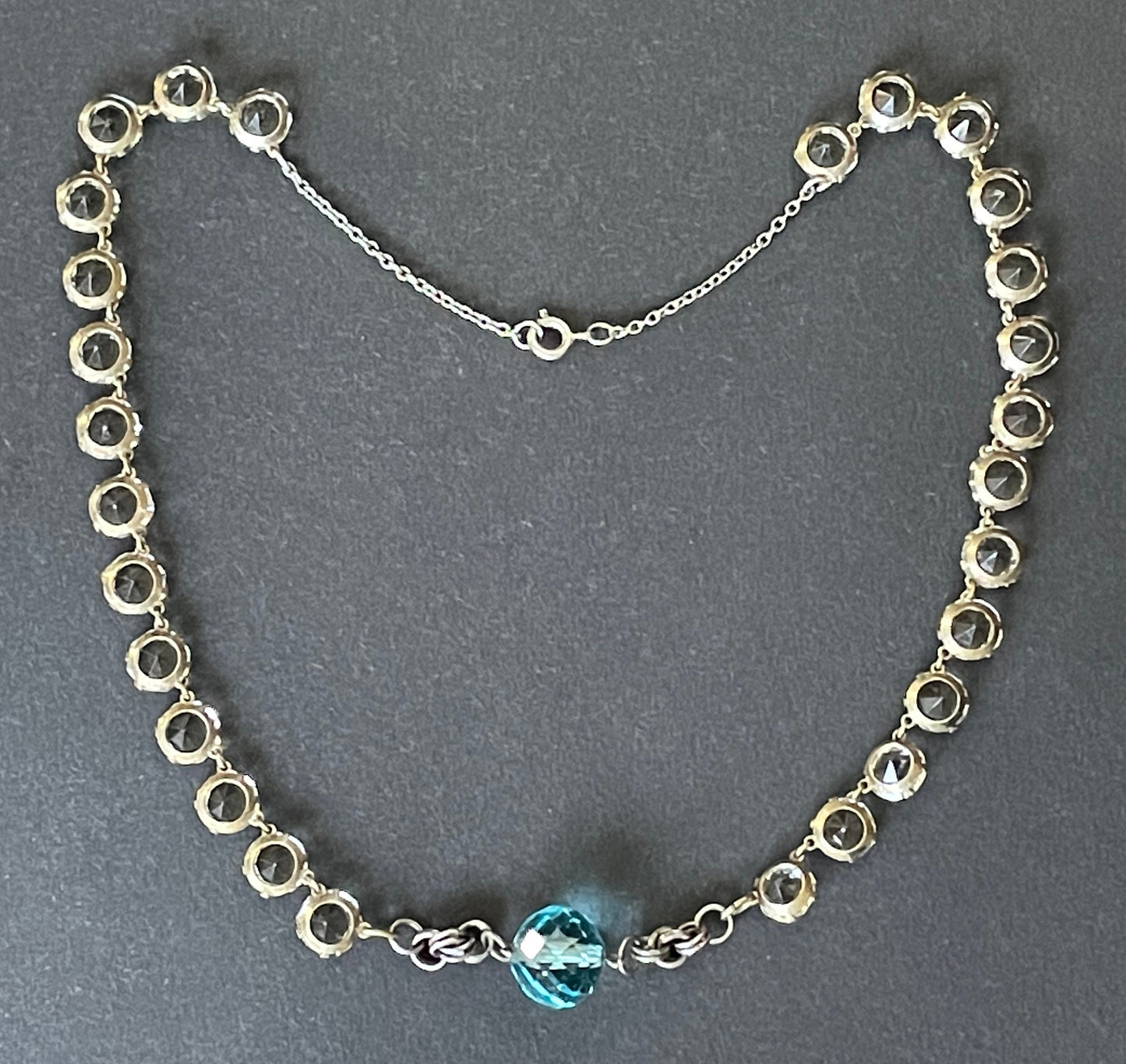 Vintage Art Deco clear paste riviere necklace with sapphire blue crystal bead and machine age link feature, bezel set open backed stones