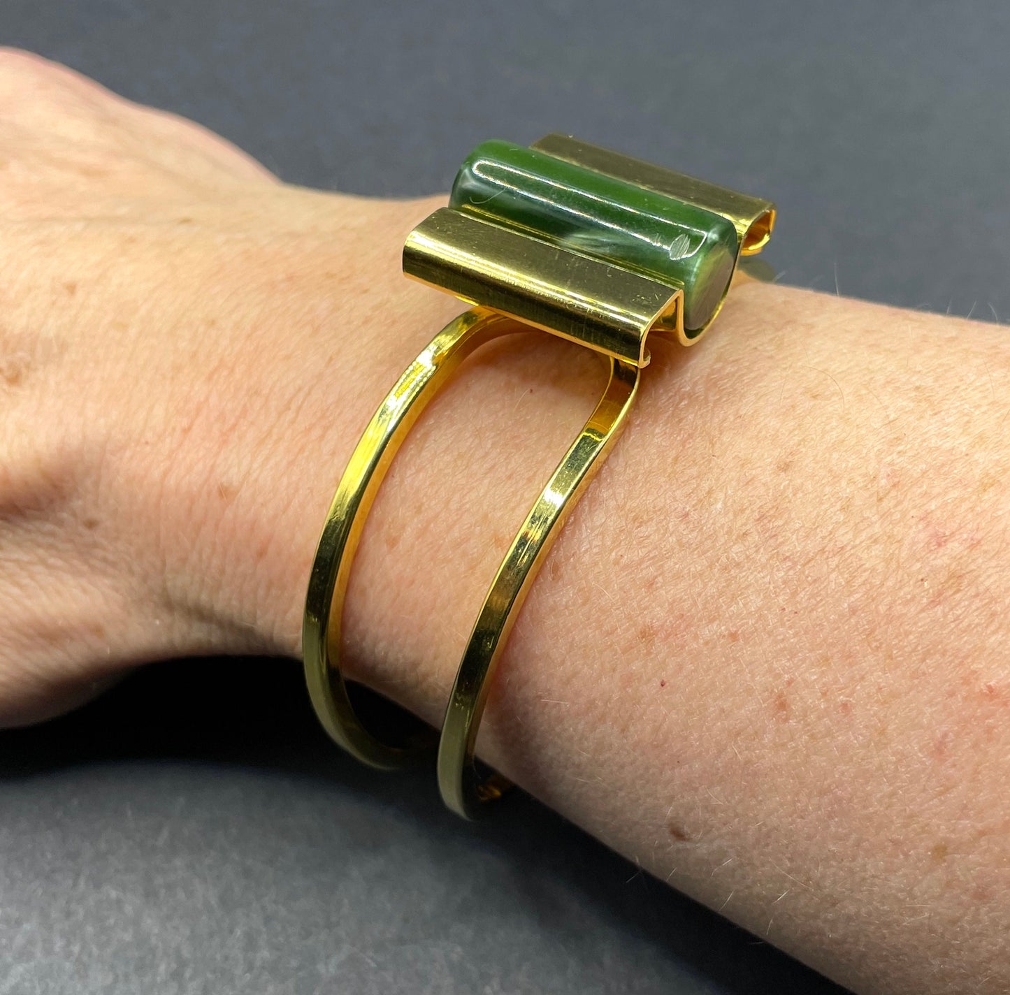 Vintage Jakob Bengel Art Deco machine age clamper bangle in shiny gold tone with a rich green galalith cylinder